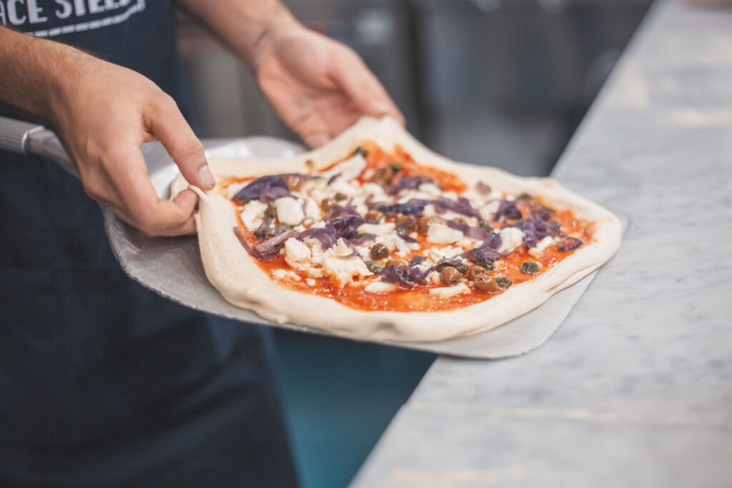 Pizza Tropeana con cipolla rossa caramellata, pomodoro, fiordilatte, olive taggiasche e capperi